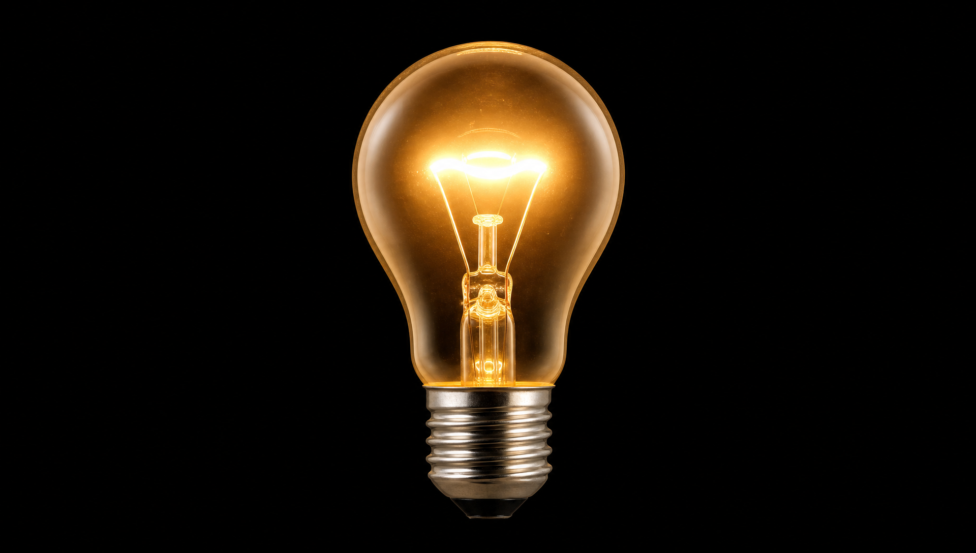 A single glowing vintage light bulb on a dark background